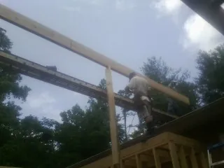 Carpenter setting a ridge beam over a new addition frame — Ice Dam Removal by Roofing Brothers in Powers Lake