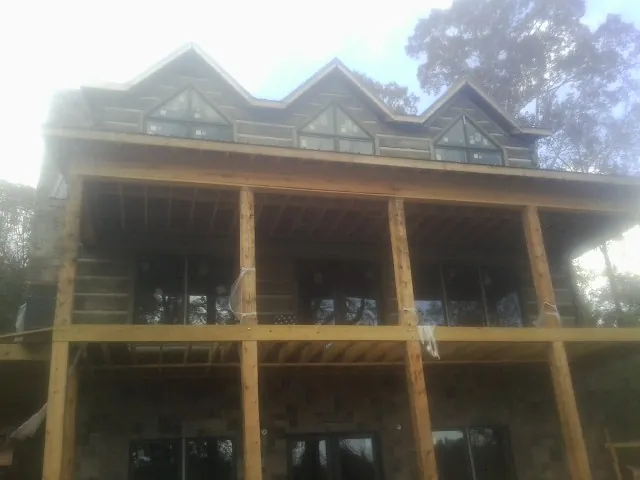 Dormers and porch framing on a large log home under construction — Roof Coating work by our crew in Powers Lake