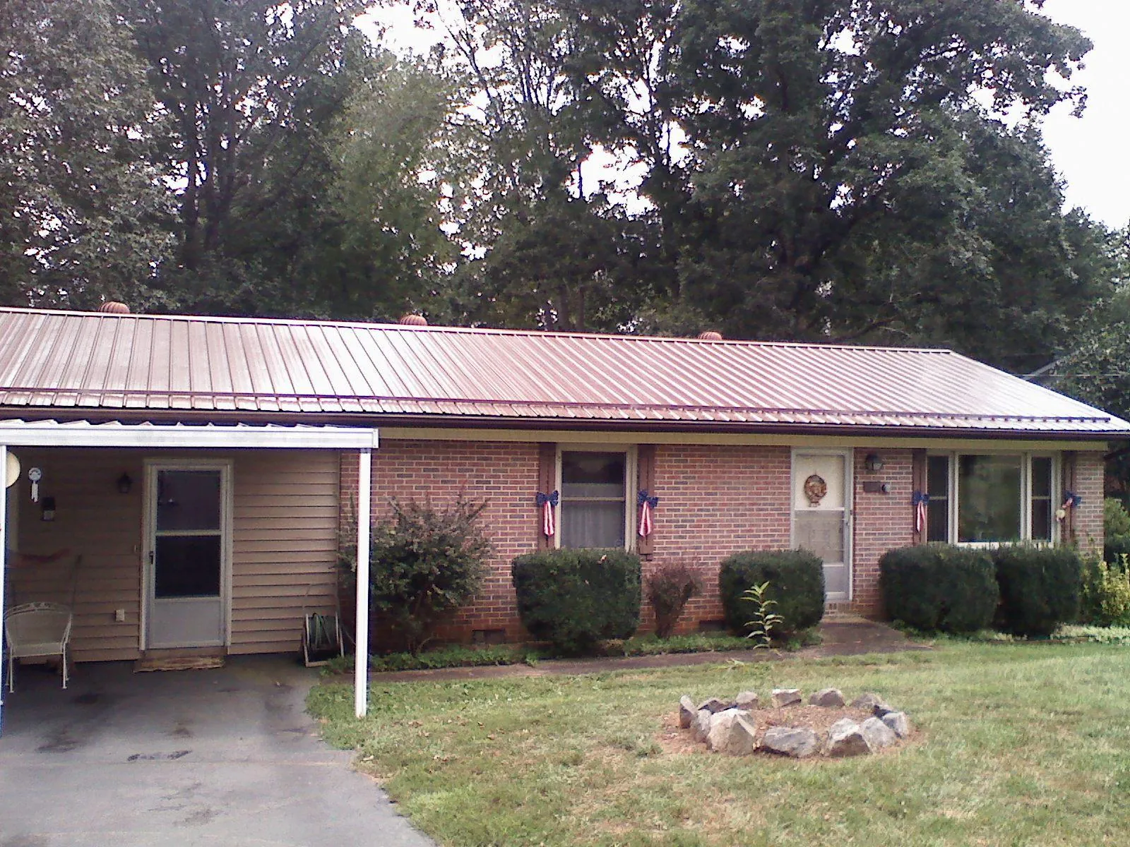 Bronze metal roof and carport on a brick ranch home — Roof Repair work by our crew in Powers Lake