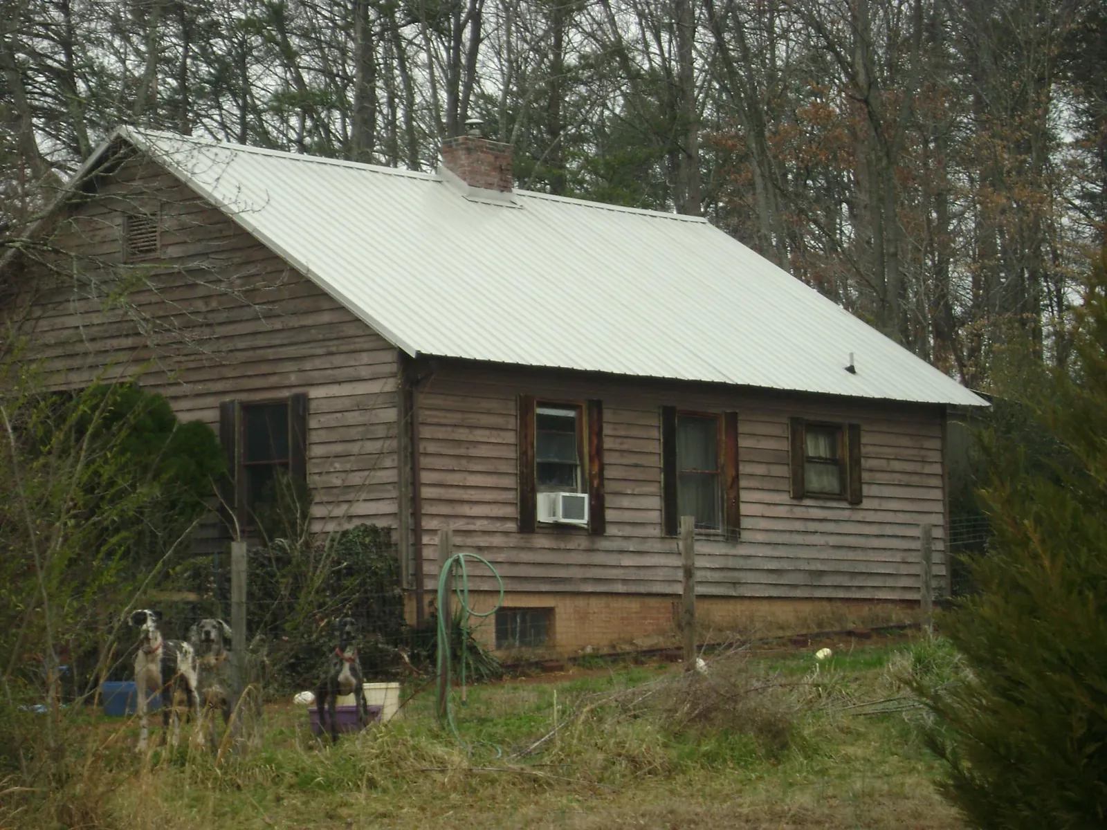 White metal roof on an old wood sided farmhouse, from a Metal Roof Installation job in Powers Lake